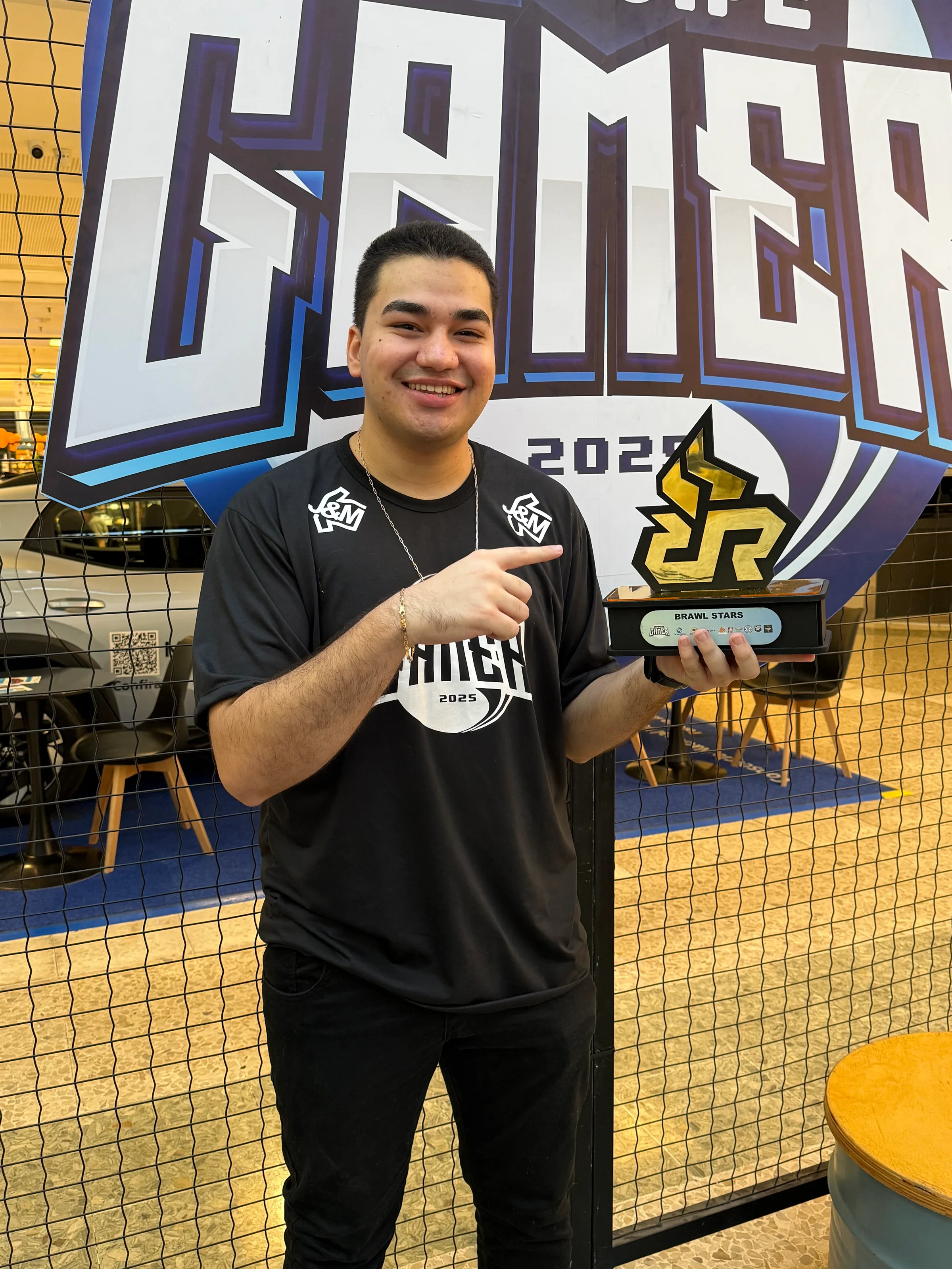 Campeão individual sorrindo e apontando pro troféu.